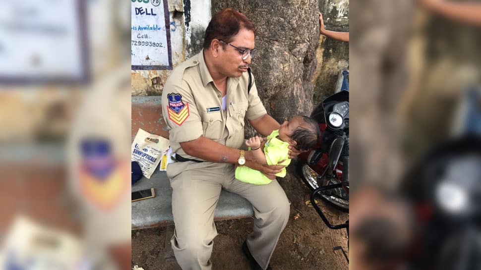 Cop babysits crying baby as mother writes exam; heartwarming photo goes viral