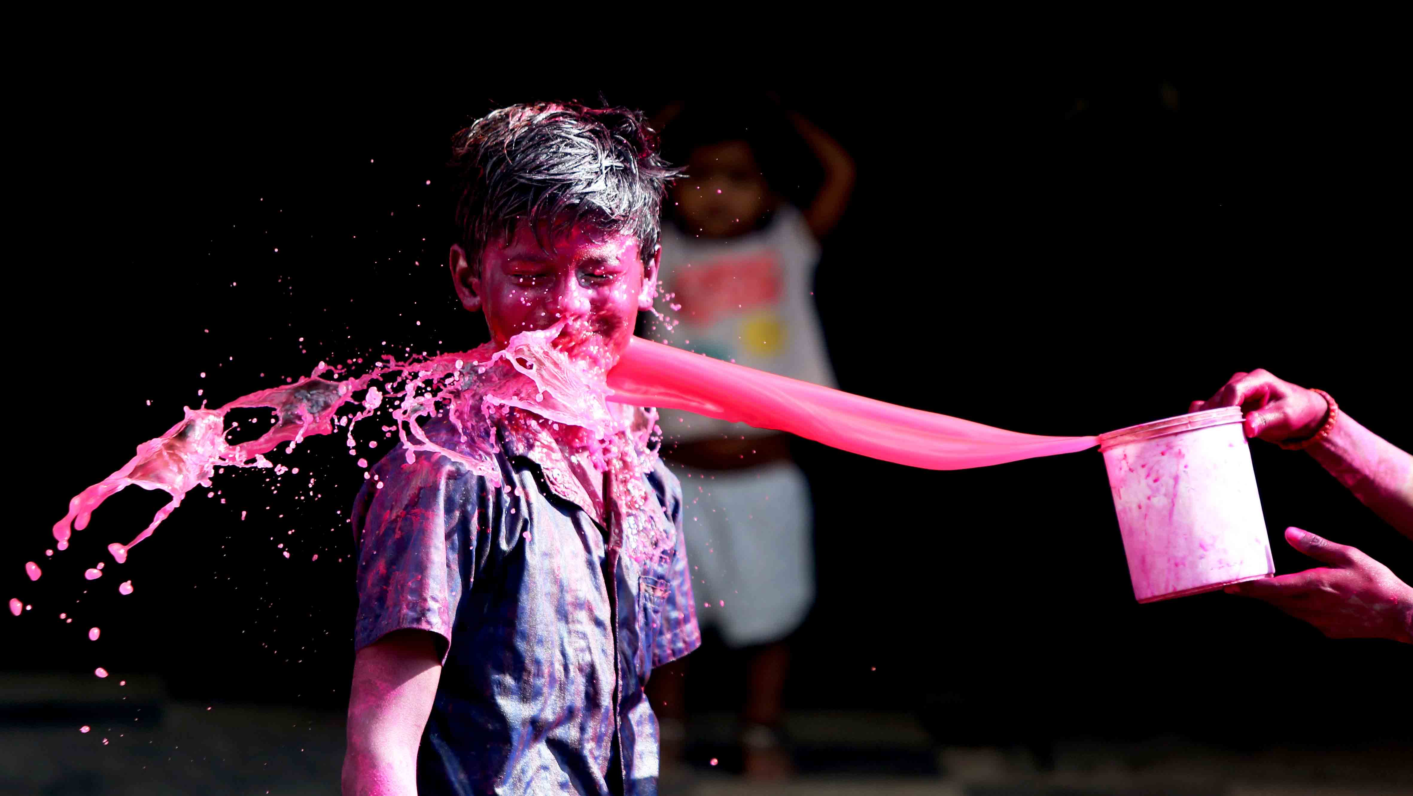 Colour water being thrown on a boy during Holi celebration