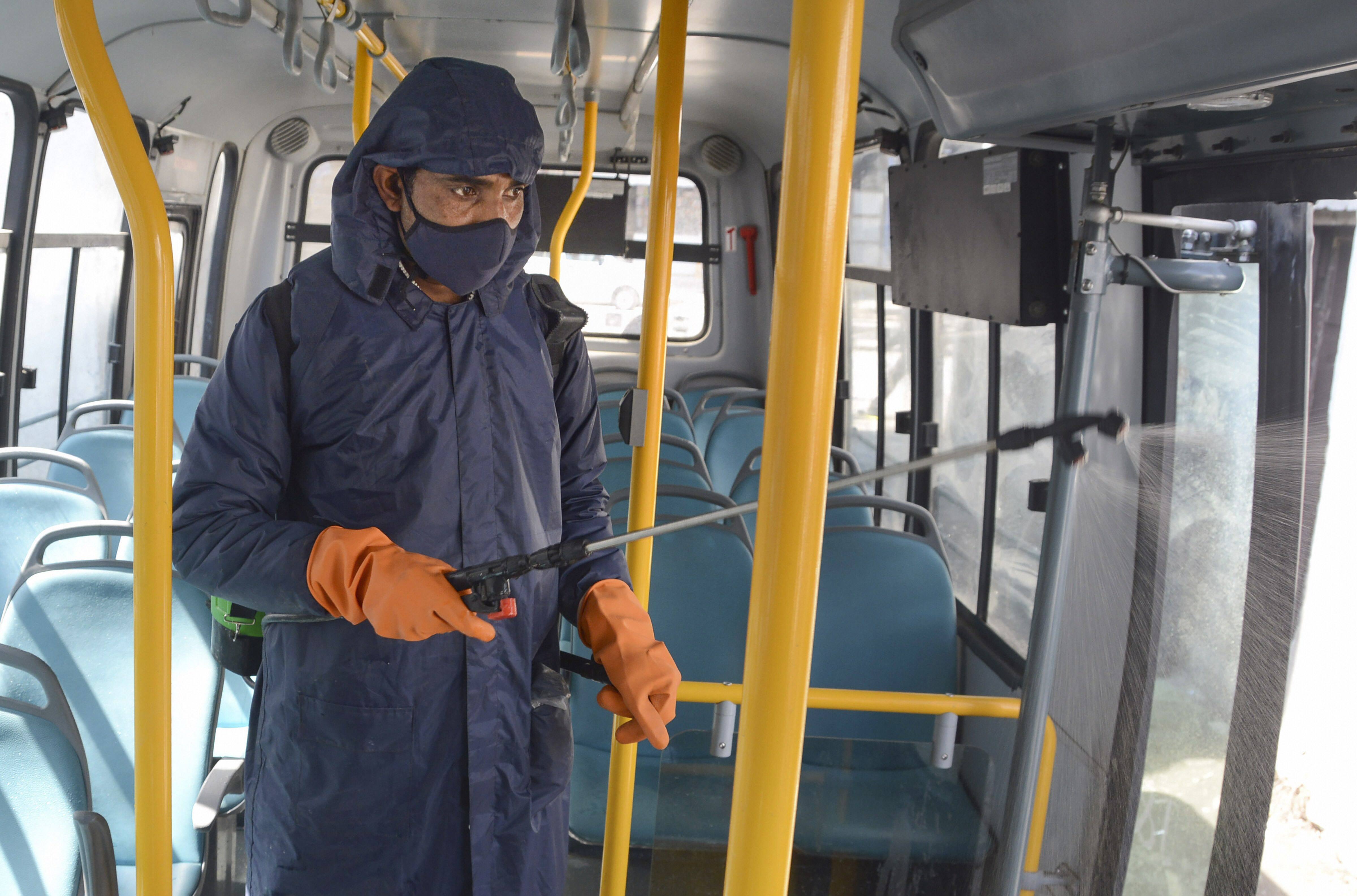 Municipal worker sprays disinfectants inside a bus