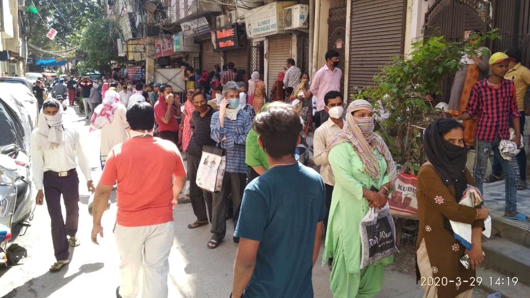 People stand outside grocery shop in Delhi's Baljit Nagar