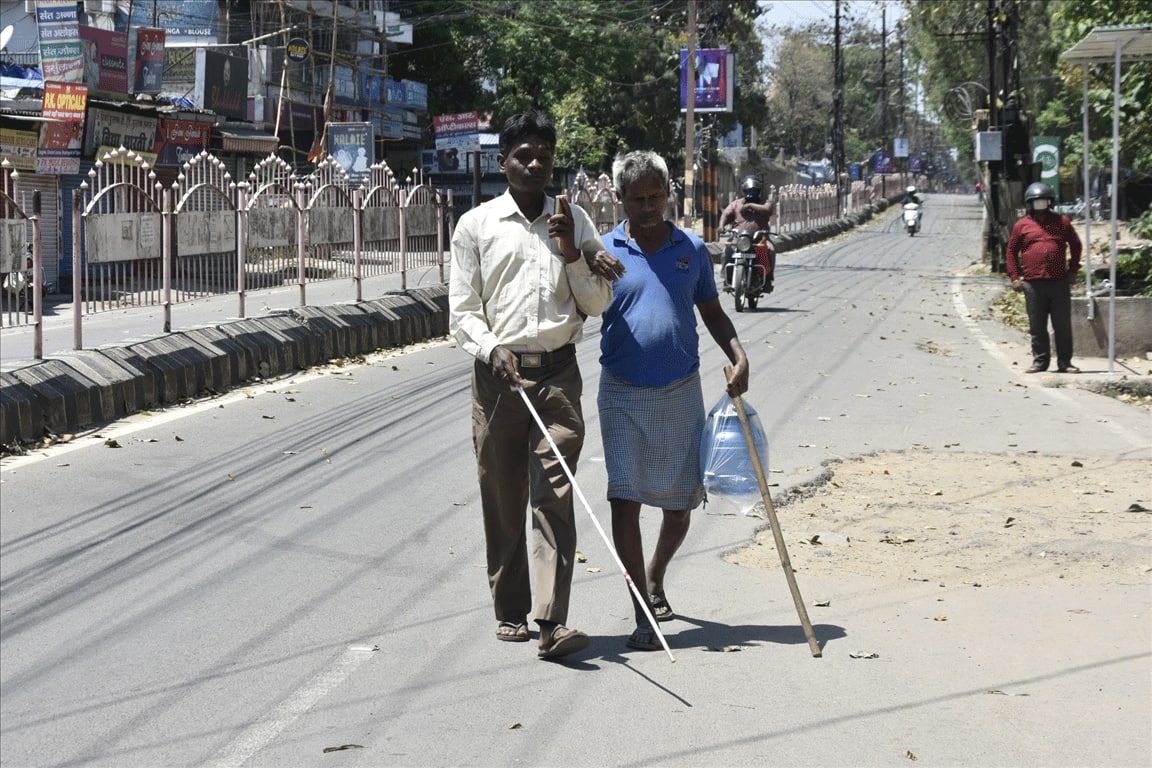 Visually impaired men head back to their shelter after purchasing a water storage container on lockdown Day 5