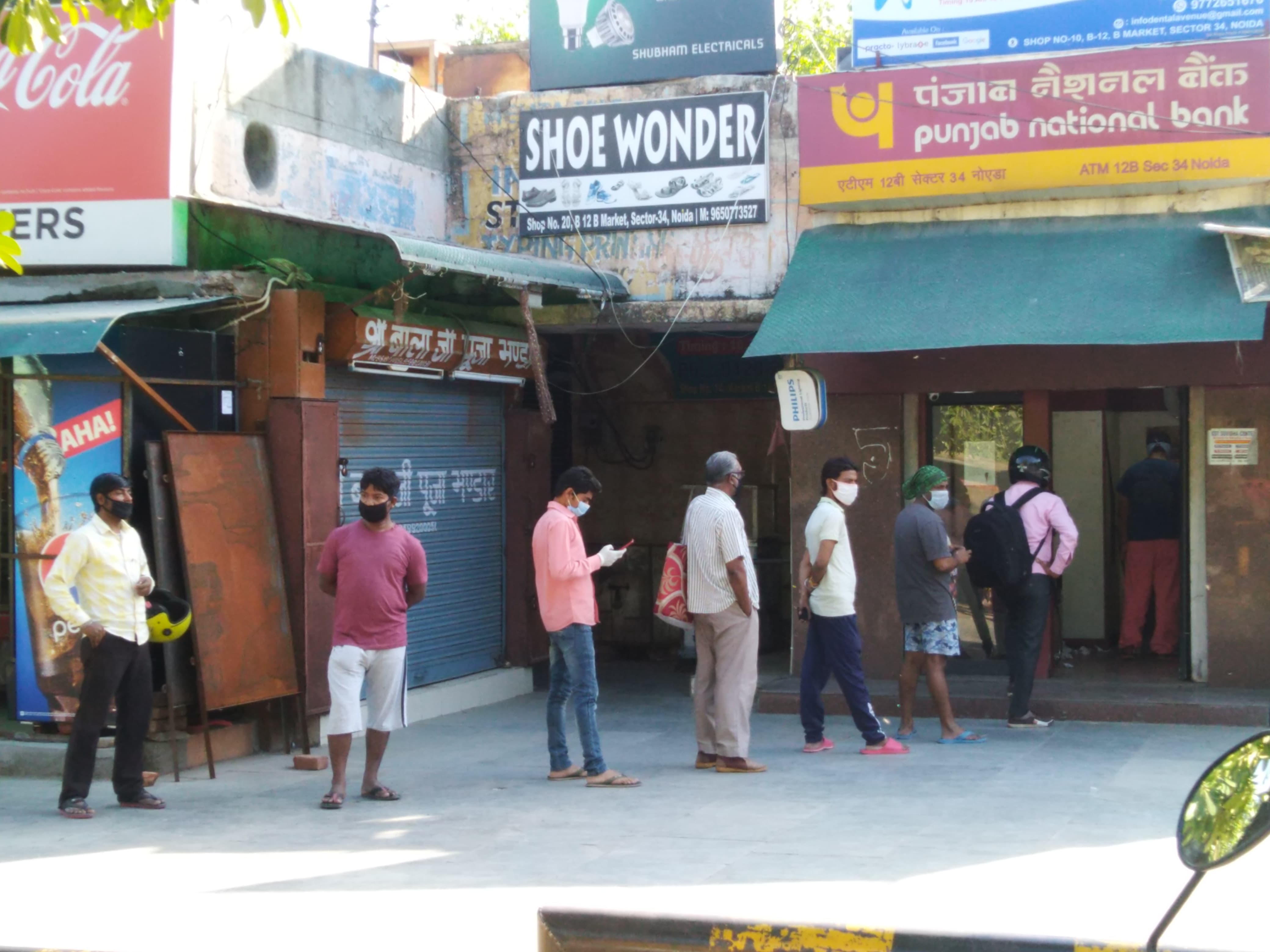 People in Noida line up in front of an ATM