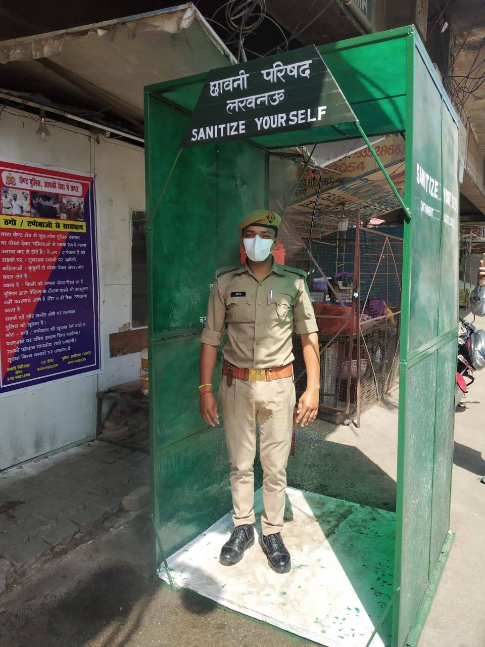 Policemen sanitize themself before entering Sadar Bazar Police station