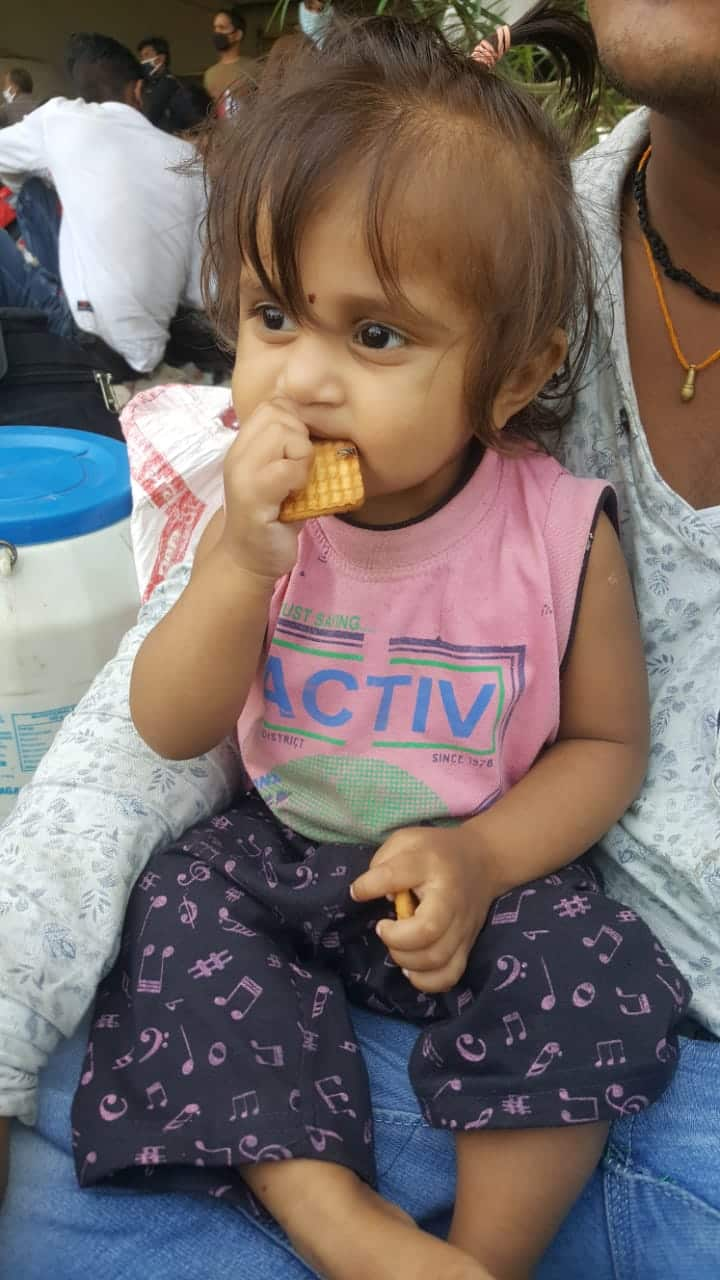 Kid of a migrant worker eating biscuit while waiting at Delhi-Ghaziabad border