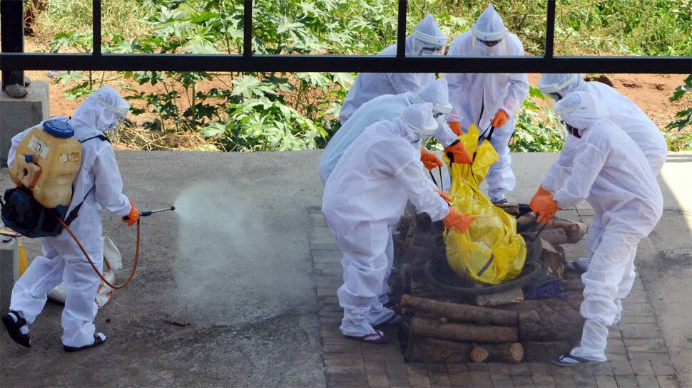 Municipal workers wearing protective suits prepare to cremate the body of a COVID-19 patient