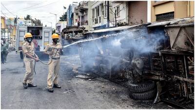 Police personnel near burnt vehicles 