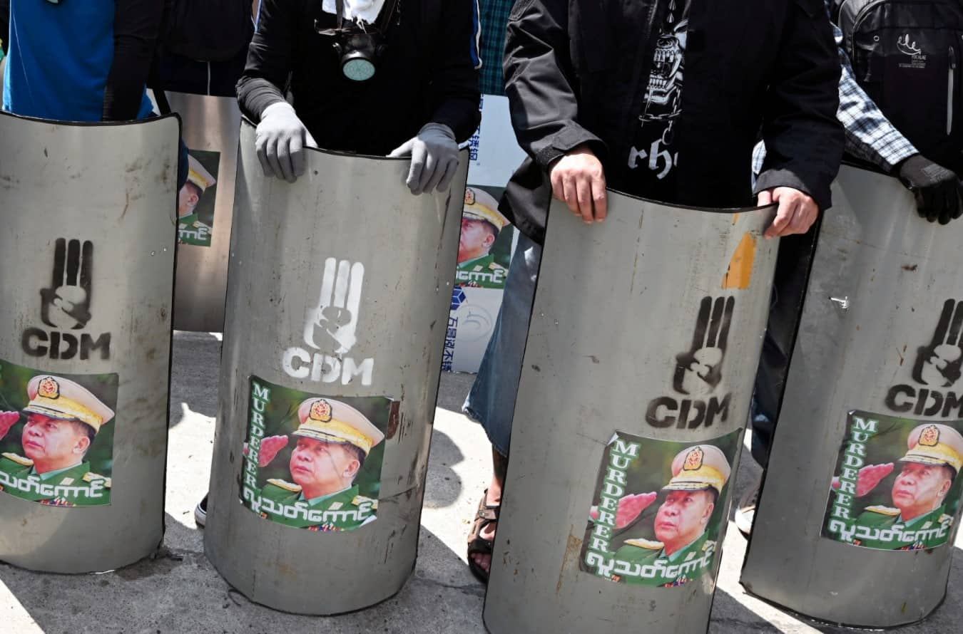 Anti-coup protesters stand behind a barricade during a demonstration