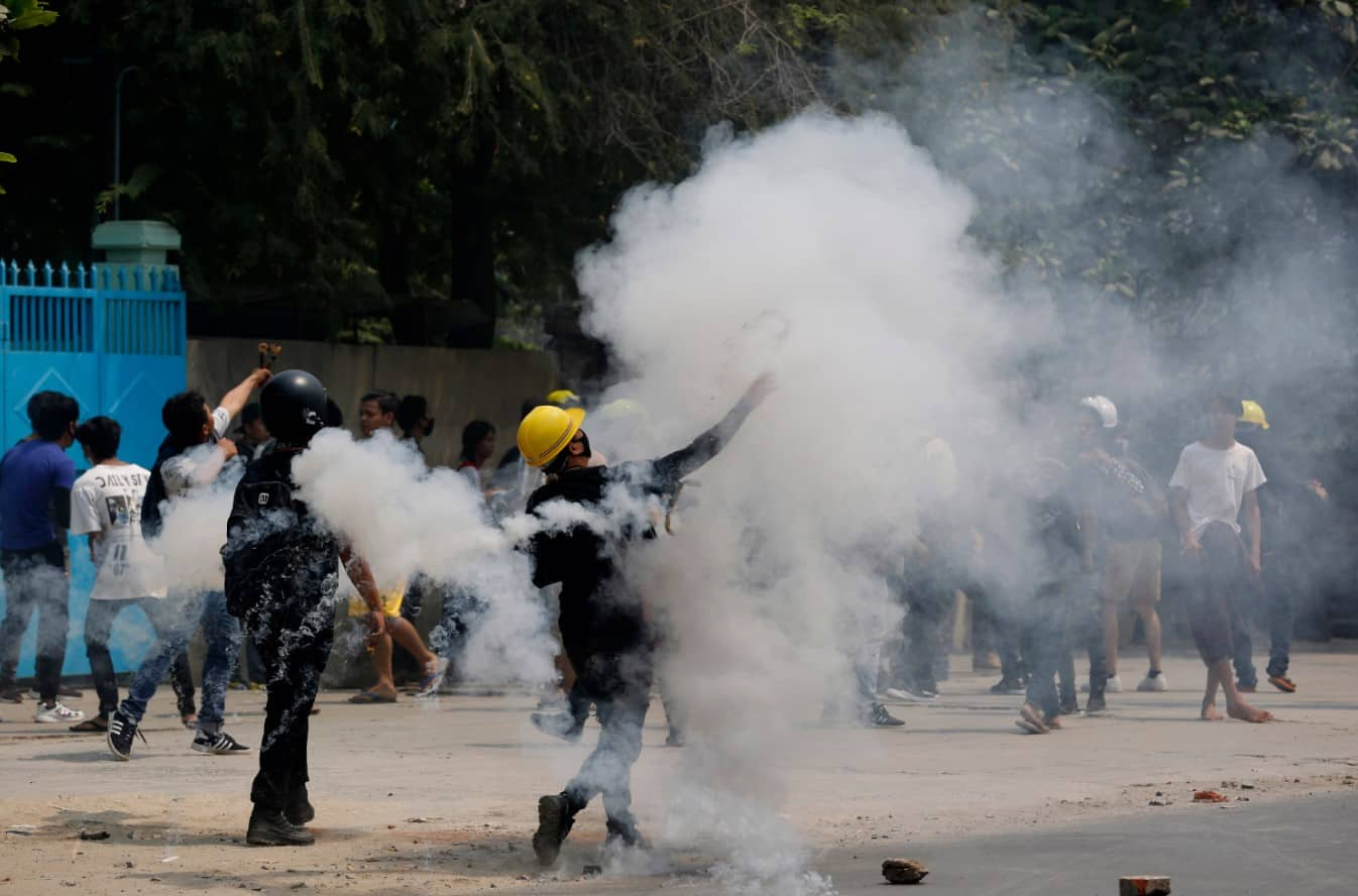 Demostrators hurl back tear gas canisters towards police during a protest against the military coup 