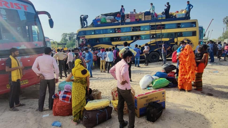 Labourers sit on top of an overcrowded bus