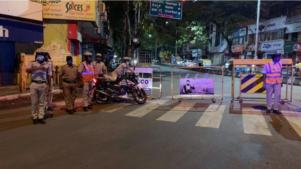 Police personnel stand guard near barricades during night Curfew in Bengaluru