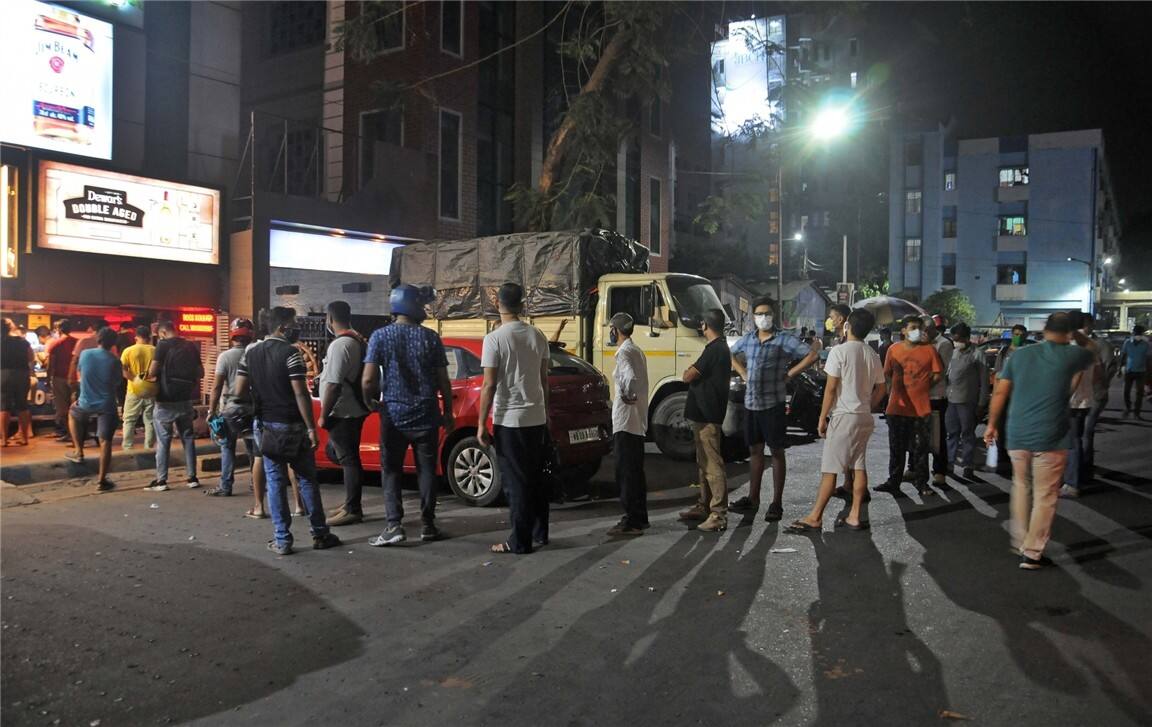 People stand in a queue at a liquor store, due to partial lockdown in West Bengal