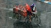 A worker carries LPG cylinders on a tricycle during rains ahead of Cyclone Yaas