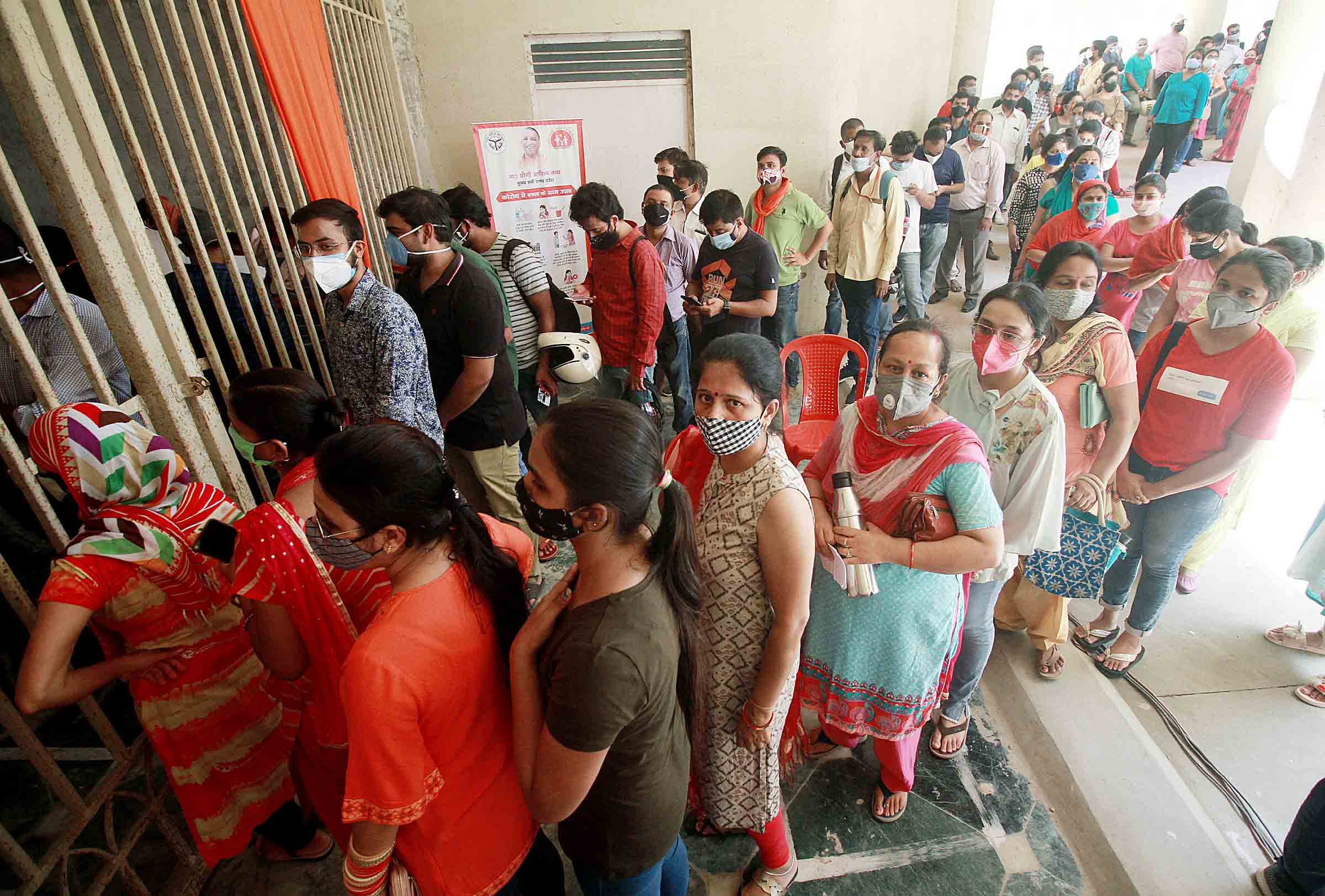 People sit in a queue as they wait to get COVID-19 vaccination