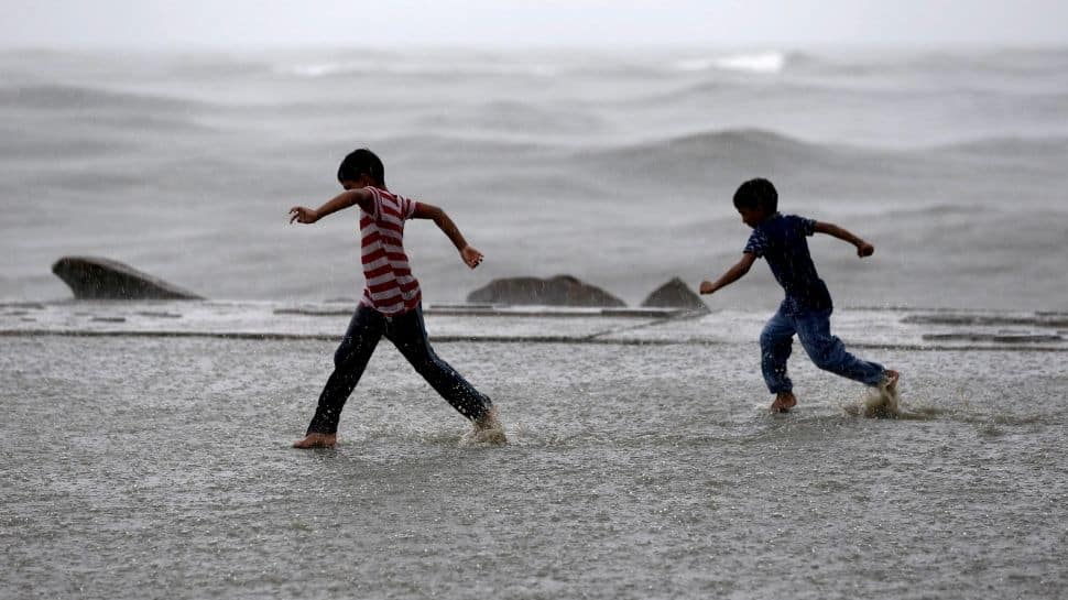 Children enjoy as it rains at a sea front in Kochi