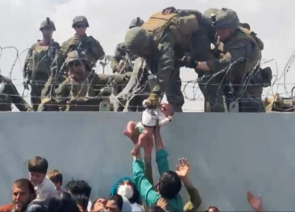 A baby is handed over to the American army over the perimeter wall of the airport in Kabul