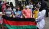 People hold the national flag of Afghanistan during a protest outside the UNHCR office