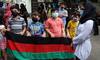 People hold the national flag of Afghanistan during a protest outside the UNHCR office