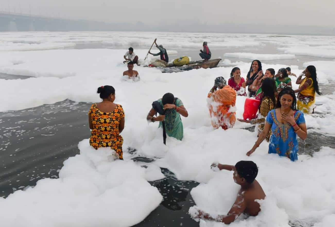 Devotees offering prayers as toxic foam floats on surface of polluted Yamuna river in Delhi