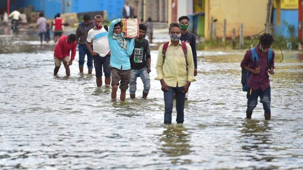 People wading through a waterlogged road 