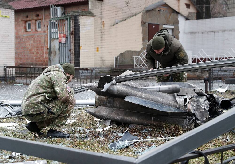 Ukrainian police inspect the remains of a missile that fell in the street in Kyiv