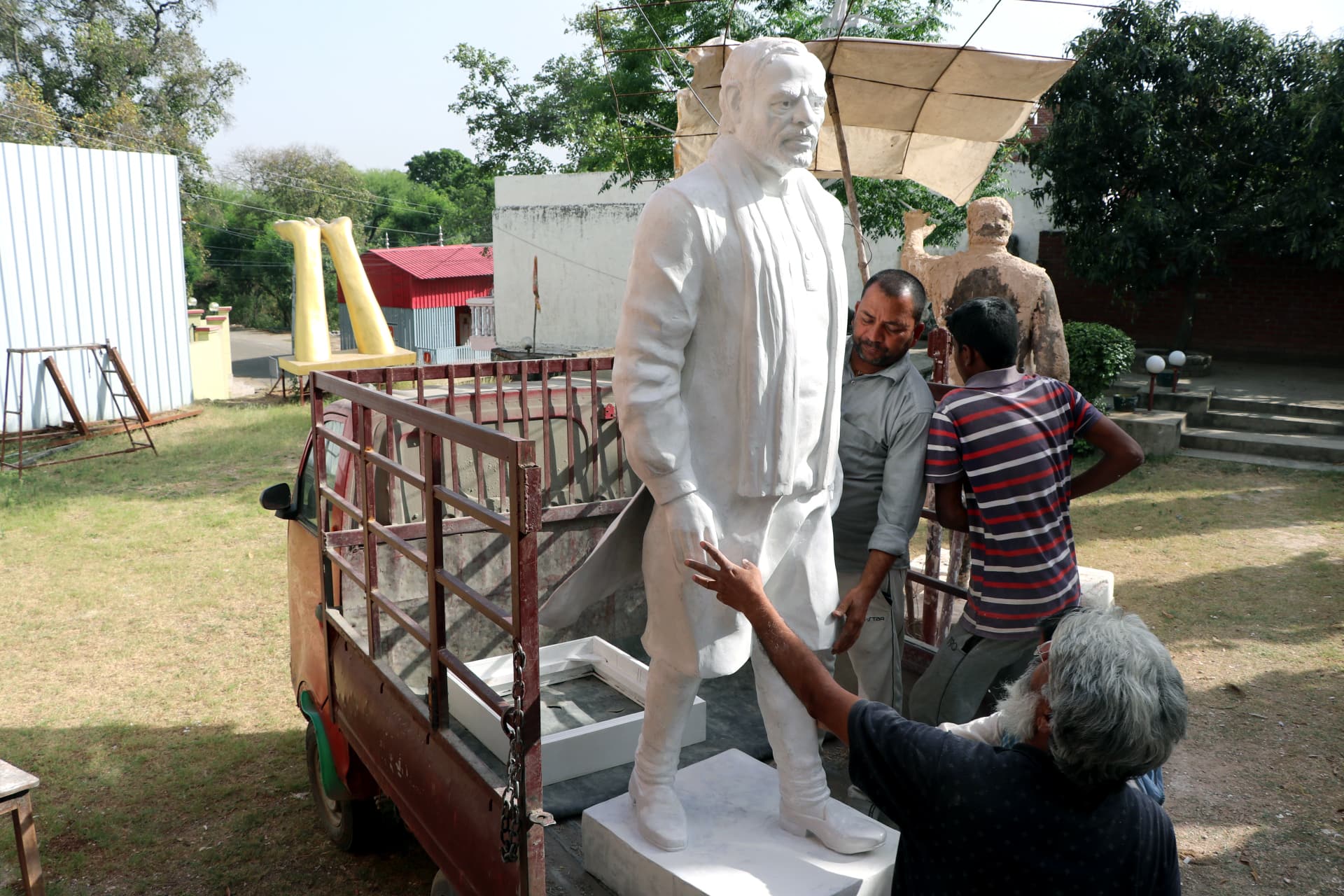 Workers carry the statue of PM Modi for the final touch ahead of his visit to Samba