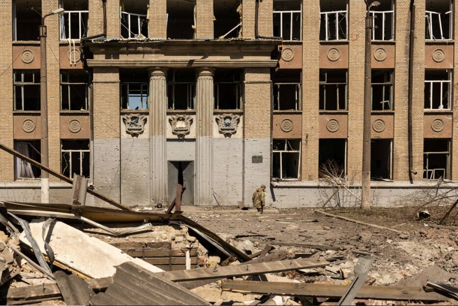 A Ukrainian soldier walks in front of a school that was bombed amid Russia's invasion in Ukraine