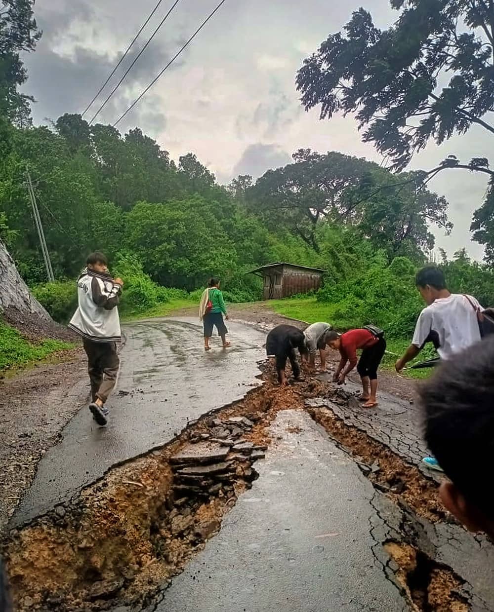 Locals inspecting a damaged road in Assam