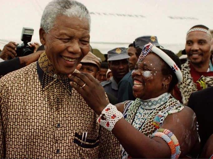 A traditionally dressed Xhosa woman adorns Nelson Mandela