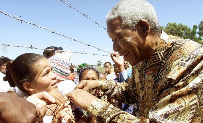 Nelson Mandela greets children during a visit to Eerste River township