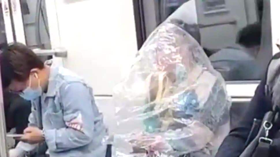 Bizarre! Chinese woman eats banana whilst covered in plastic sheet on subway train