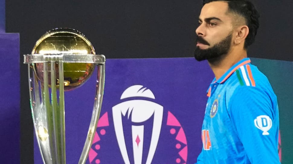 Virat Kohli walks past the trophy