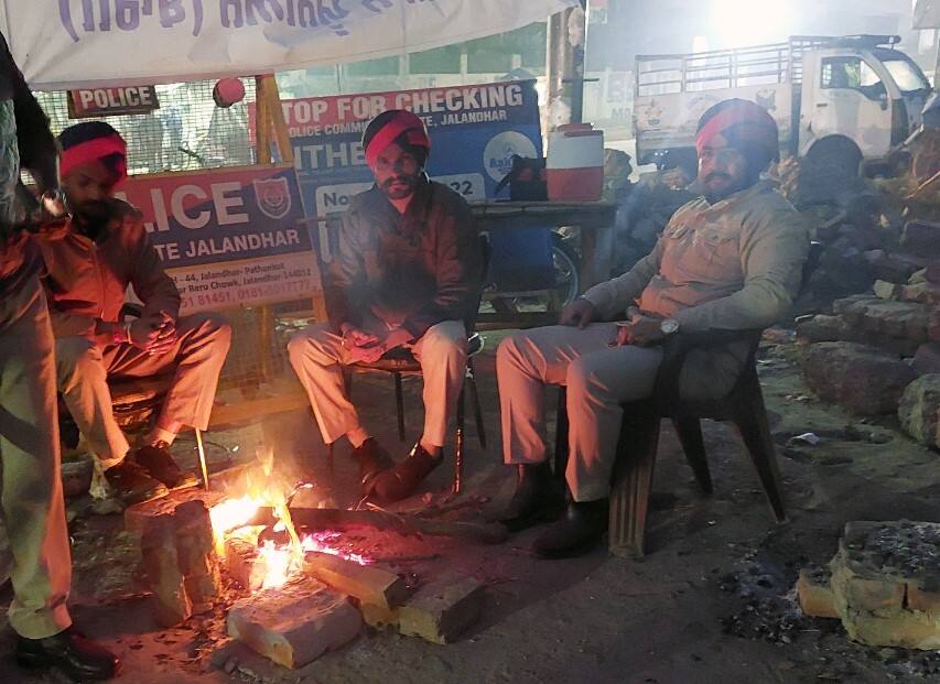 Policemen sit around a fire to stay warm during a cold winter morning, in Jalandhar on Tuesday