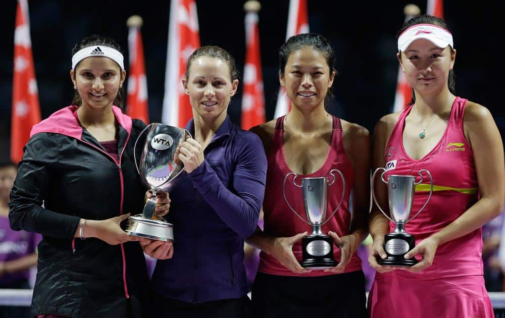 India's Sania Mirza, left, and Zimbabwe's Cara Black, second left, hold their trophy after defeating Taiwain's Hsieh Su-Wei and China's Peng Shuai, right, in the doubles final at the WTA tennis finals in Singapore.