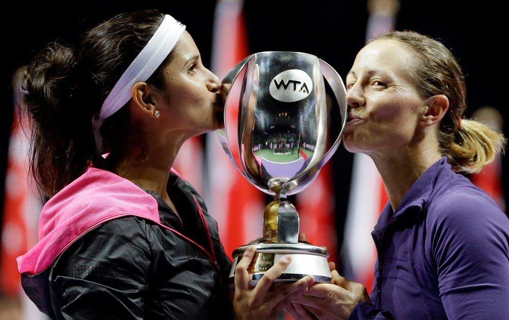 India's Sania Mirza, left, and Zimbabwe's Cara Black kiss their trophy after defeating Taiwain's Hsieh Su-Wei and China's Peng Shuai in the doubles final at the WTA tennis finals in Singapore.