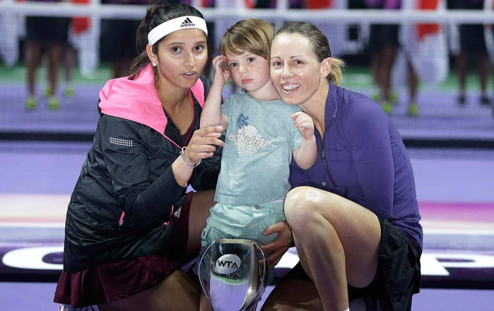 India's Sania Mirza, left, and Zimbabwe's Cara Black with her son Lachlan pose with their trophy after defeating Taiwan's Hsieh Su-Wei and China's Peng Shuai in the doubles final at the WTA tennis finals in Singapore.