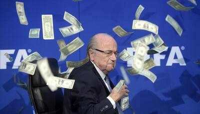 British comedian showers Sepp Blatter with fake money during press conference