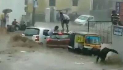 Watch: Two cars get washed away on flooded street moments after narrow escape for occupants