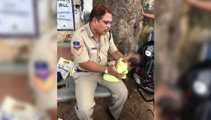 Cop babysits crying baby as mother writes exam; heartwarming photo goes viral