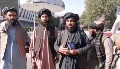 Are you happy? Taliban insurgents with rifle, reporter's microphone in hand, ask locals