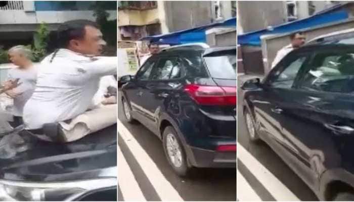 Cop sits on car bonnet to stop traffic violator, man drives off to dodge fine - Watch