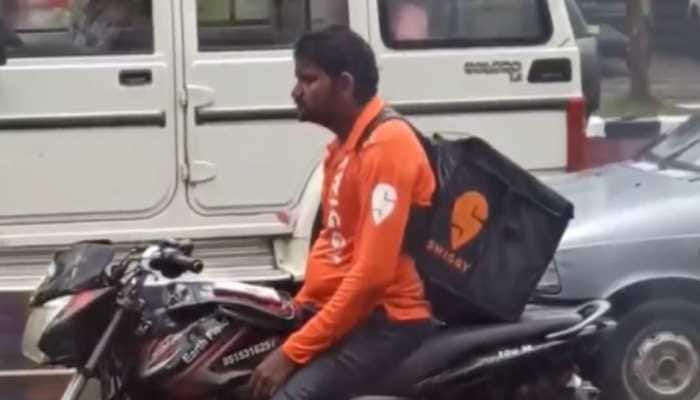 Swiggy agent gets completely drenched waiting at traffic signal in heavy rain: Watch heart-wrenching video 