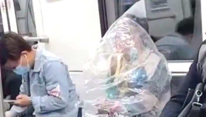 Bizarre! Chinese woman eats banana whilst covered in plastic sheet on subway train
